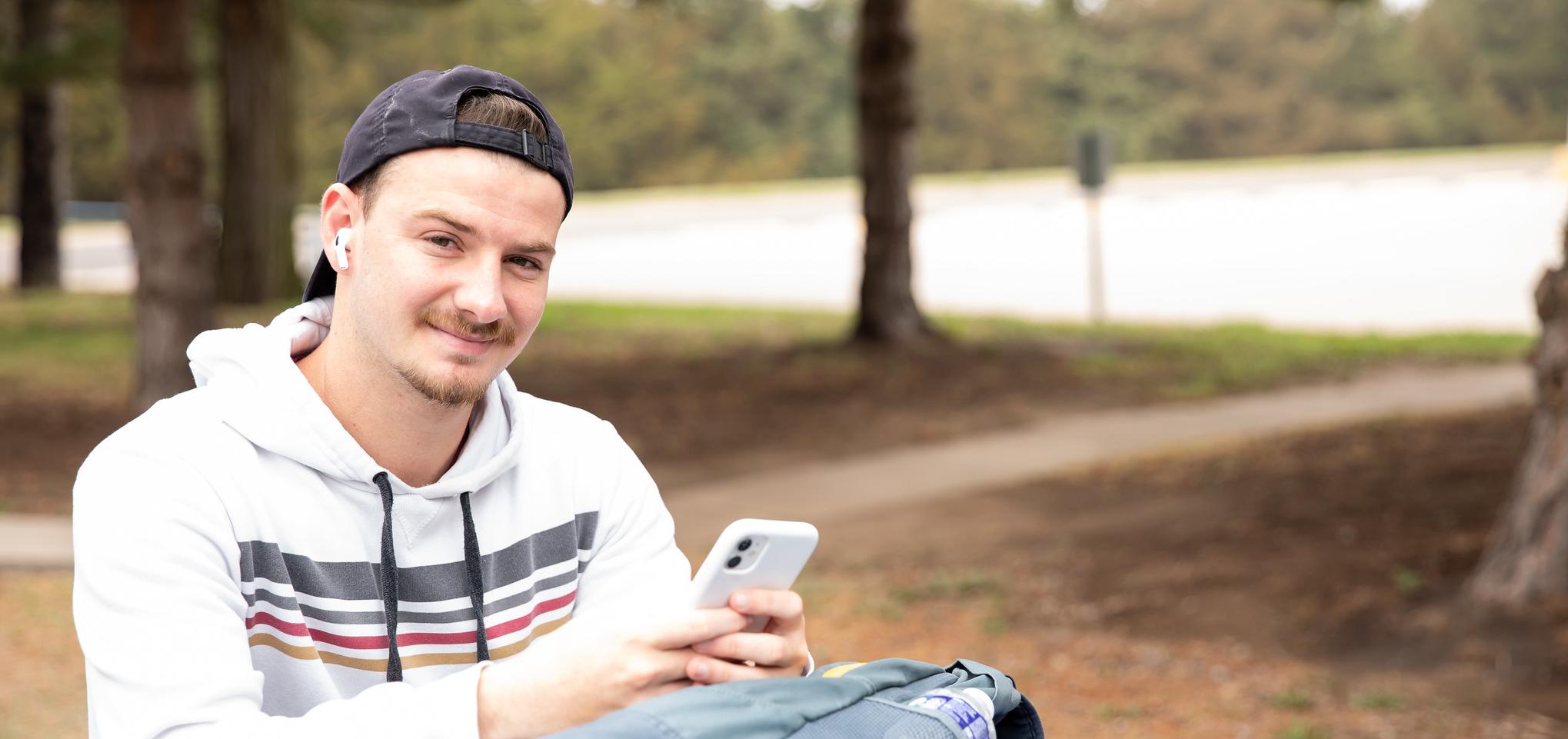 Student in white hoodie with phone